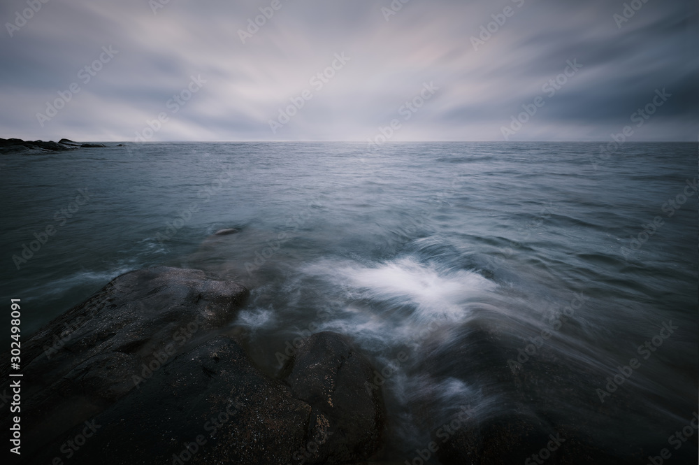 Long exposure and waves hitting the rocks in the foreground bad weather and horizon with rocks in the background