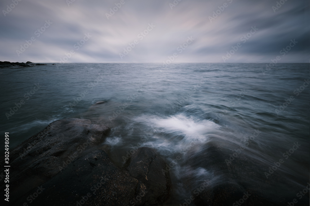 Long exposure and waves hitting the rocks in the foreground bad weather and horizon with rocks in the background Long exposure and waves hitting the rocks in the foreground bad weather and horizon with rocks in the background