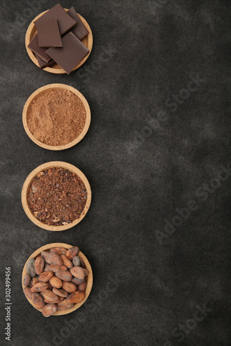 organic cacao beans, cocoa powder, ground and chocolate on a black background with copy space for text. Flat lay, top view. Ingredient. Vegan food. Background, pattern, card, menu. Vertical photo.