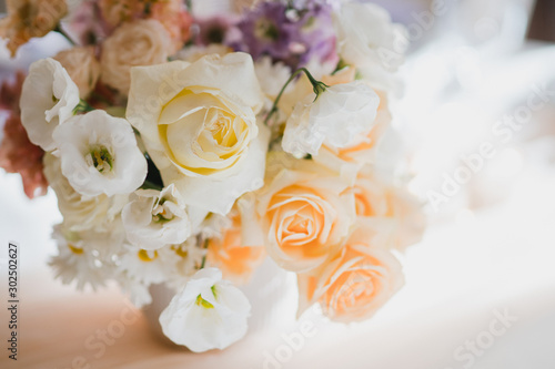 Coziness and style. Modern event design. Table setting at wedding reception. Floral compositions with beautiful flowers and greenery, candles, laying and plates on decorated table.