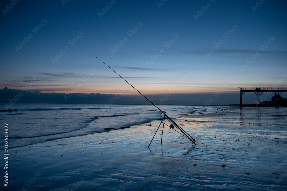 Fishing rod ready at low tide with beautiful sunset on Bognor Regis Beach.