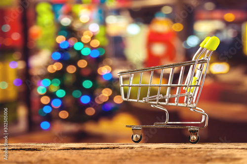 Miniature shopping cart over blurred bokeh Christmas background,for holiday shopping concept.