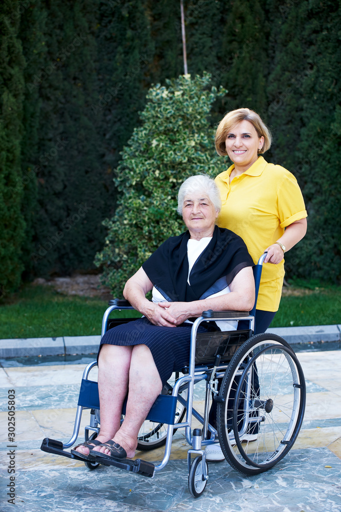 Obraz premium Volunteer caregiver and handicapped senior woman, outdoors