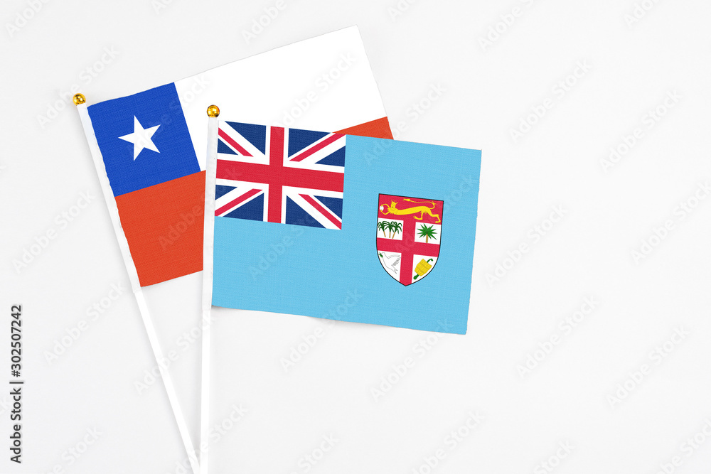 Fototapeta premium Fiji and Chile stick flags on white background. High quality fabric, miniature national flag. Peaceful global concept.White floor for copy space.