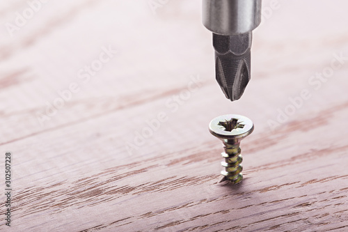 Photography screwdriver screw in a wood oaks plank