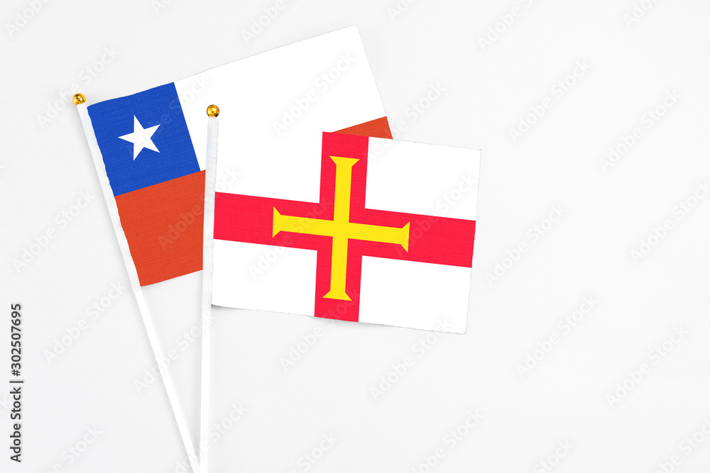 Guernsey and Chile stick flags on white background. High quality fabric, miniature national flag. Peaceful global concept.White floor for copy space.