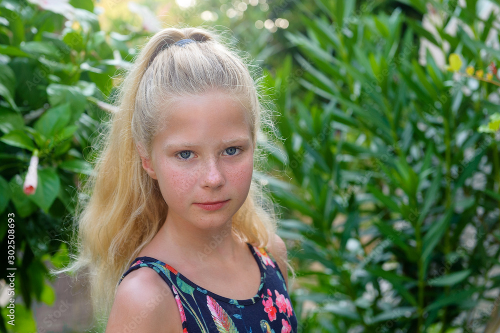 Beautiful little blonde girl with long hair, teenager, in the garden, summer Beautiful little blonde girl with long hair, teenager, in the garden, summer
