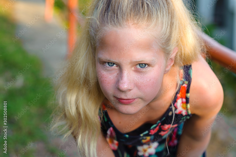 Beautiful little blonde girl with long hair in the garden, summer, portrait, smiling, emotion Beautiful little blonde girl with long hair in the garden, summer, portrait, smiling, emotion