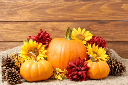 pumpkins with fall flowers arranged on a rustic wooden background. Fall background