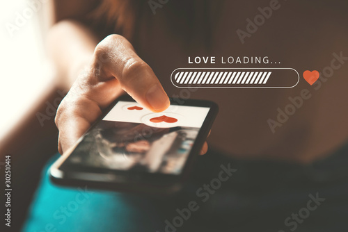 Love loading progress, Finger of woman pushing heart icon on screen in mobile smartphone application. Online dating app, valentine's day concept. photo