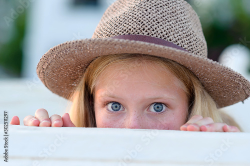 Tableau sur toile Beautiful little blonde girl with long hair in a wicker hat peeps out, summer, p