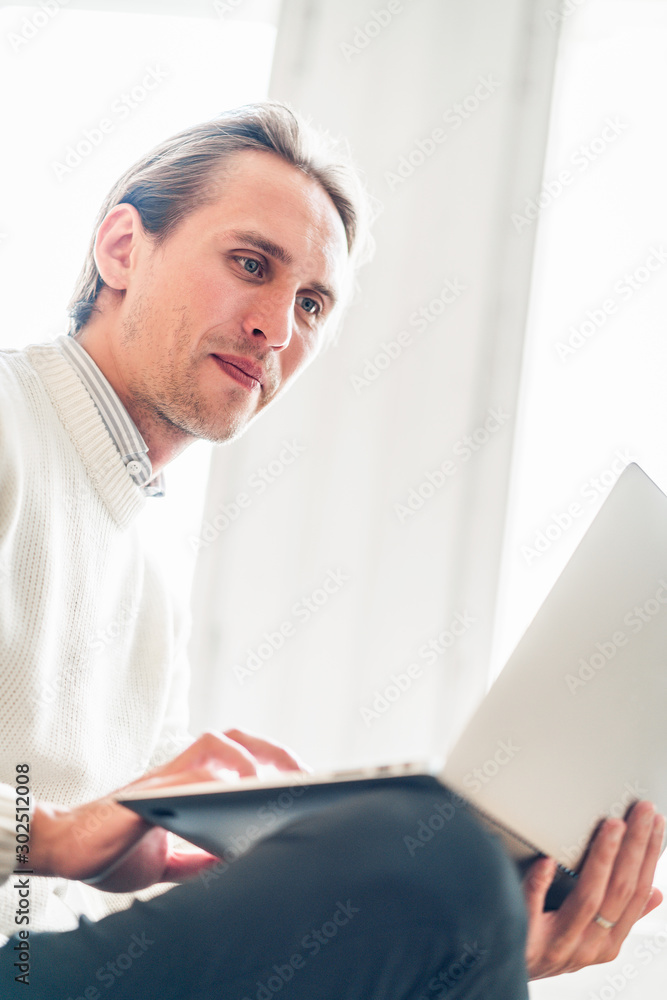 Young man looking at his portable computer. Bright light in the background. Young man looking at his portable computer. Bright light in the background.