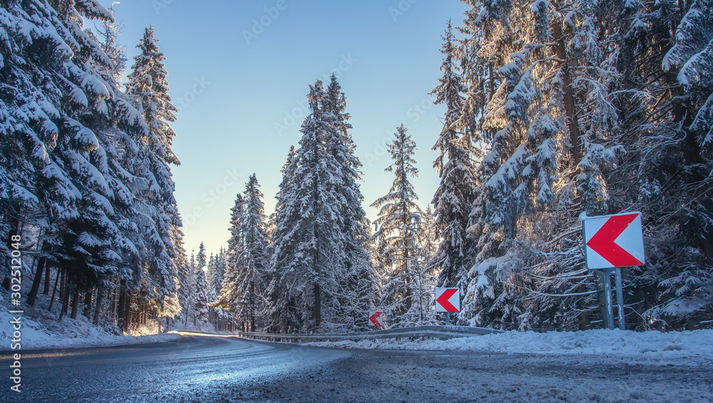 Winter nature landscape with asphalt road in clear frosty morning. Snowy trees along highway. Travel to Christmas holidays to mountains