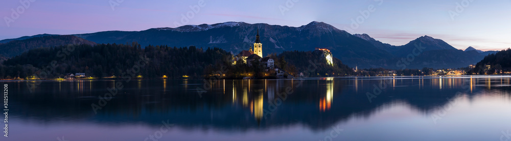 Panorama of lake Bled and Pilgrimage Church of the Assumption of Maria with reflection in the water in the twilight 