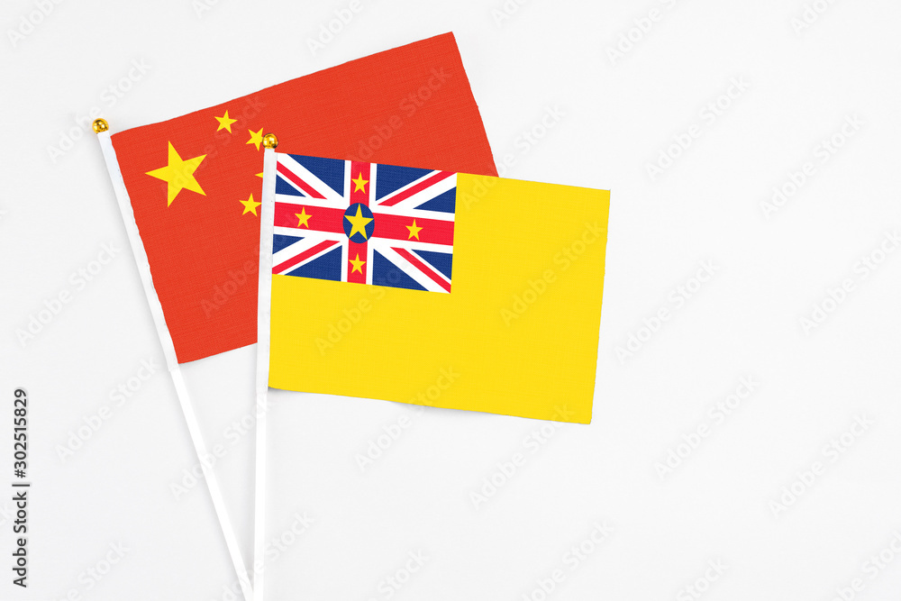 Niue and China stick flags on white background. High quality fabric, miniature national flag. Peaceful global concept.White floor for copy space. Niue and China stick flags on white background. High quality fabric, miniature national flag. Peaceful global concept.White floor for copy space.