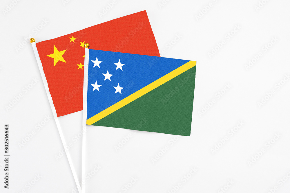 Solomon Islands and China stick flags on white background. High quality fabric, miniature national flag. Peaceful global concept.White floor for copy space. Solomon Islands and China stick flags on white background. High quality fabric, miniature national flag. Peaceful global concept.White floor for copy space.