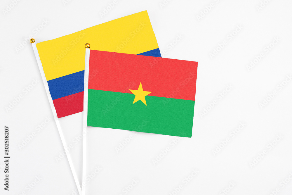 Burkina Faso and Colombia stick flags on white background. High quality fabric, miniature national flag. Peaceful global concept.White floor for copy space. Burkina Faso and Colombia stick flags on white background. High quality fabric, miniature national flag. Peaceful global concept.White floor for copy space.