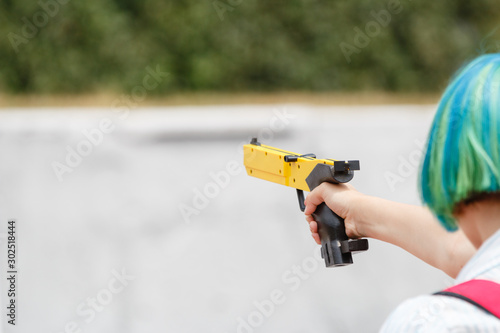 Girl with a yellow laser sport gun aims closeup
