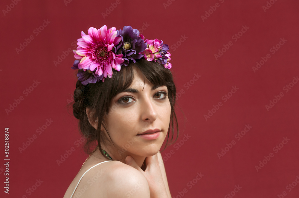 Young woman dancing with white dress and flowers in her hair. Red background.