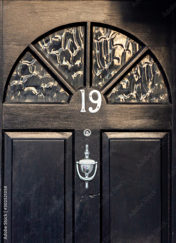 Black wooden front door with the house number 19 Black wooden front door with the house number 19