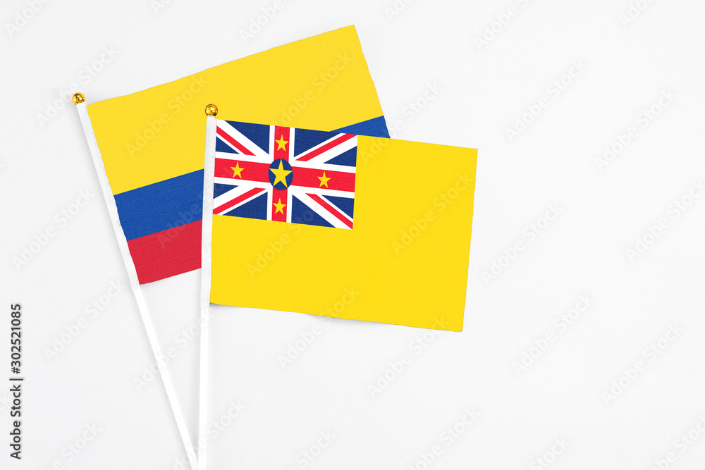 Niue and Colombia stick flags on white background. High quality fabric, miniature national flag. Peaceful global concept.White floor for copy space. Niue and Colombia stick flags on white background. High quality fabric, miniature national flag. Peaceful global concept.White floor for copy space.