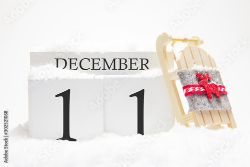 Wooden calendar for December, 11 th day of the winter month. The symbols of winter are snow and sleigh. Concept of holidays, vacation and winter fun.