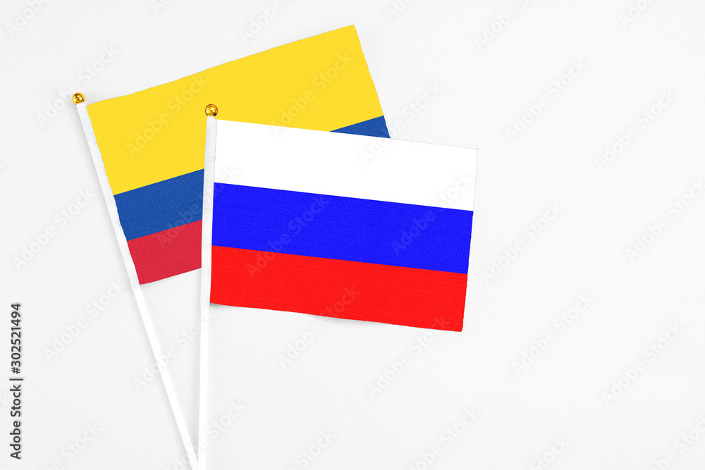 Russia and Colombia stick flags on white background. High quality fabric, miniature national flag. Peaceful global concept.White floor for copy space. Russia and Colombia stick flags on white background. High quality fabric, miniature national flag. Peaceful global concept.White floor for copy space.