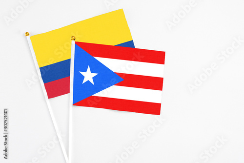 Puerto Rico and Colombia stick flags on white background. High quality fabric, miniature national flag. Peaceful global concept.White floor for copy space.