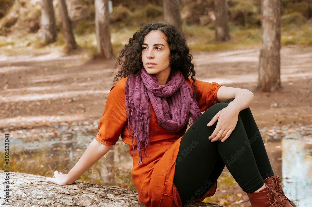 Young woman, dressed in casual clothes, with relaxed attitude, in a forest with autumn colors.