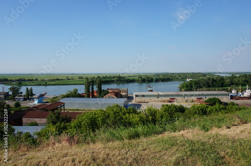 Warehouse facilities on the port territory. Port crane on the river Bank. Summer natural landscape. © Станислав 
