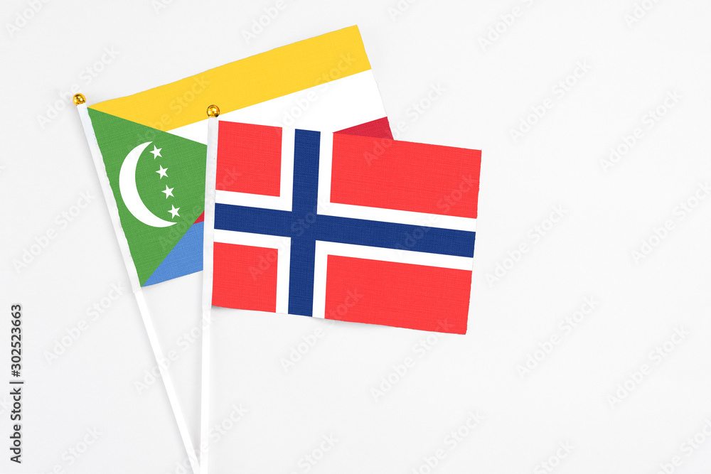 Bouvet Islands and Comoros stick flags on white background. High quality fabric, miniature national flag. Peaceful global concept.White floor for copy space.