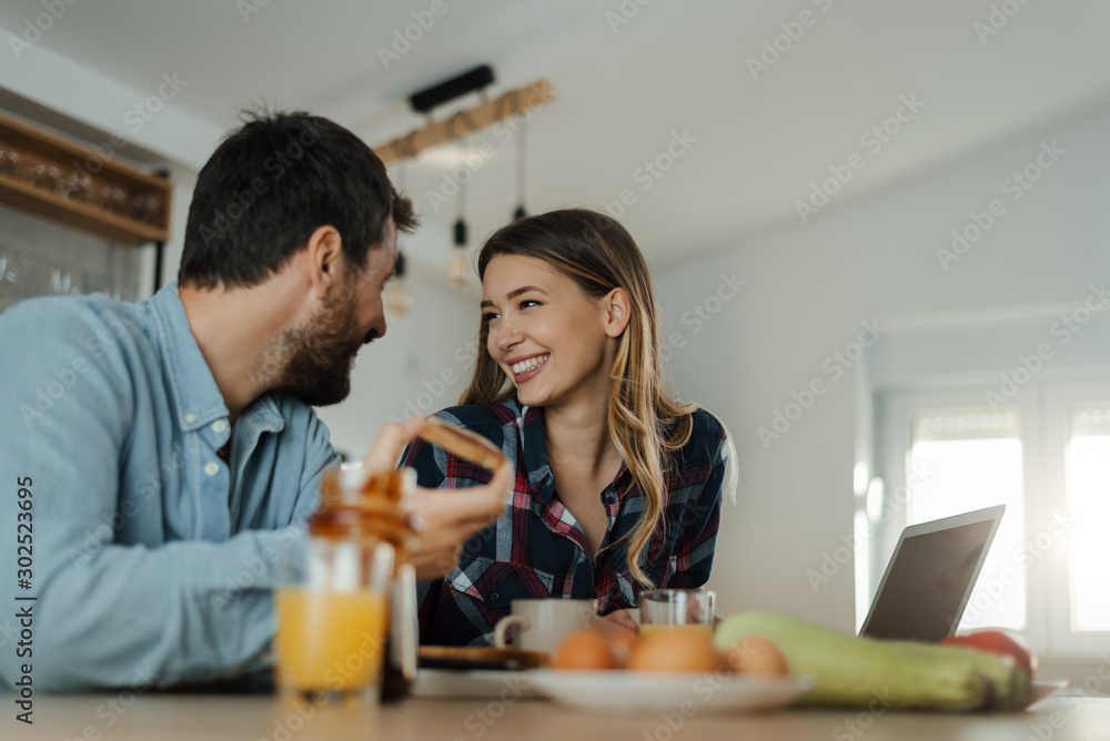 Young smiling couple communicating during breakfast time in the kitchen Young smiling couple communicating during breakfast time in the kitchen