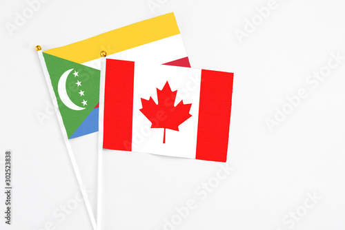 Canada and Comoros stick flags on white background. High quality fabric, miniature national flag. Peaceful global concept.White floor for copy space. photo