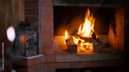 Focus and camera move from a bottle of red wine and a wine glass to a fireplace with flaming fire. Alcoholic drink concept. Fire background. Drink alone. Restaurant Beverage. Beverage Close up
