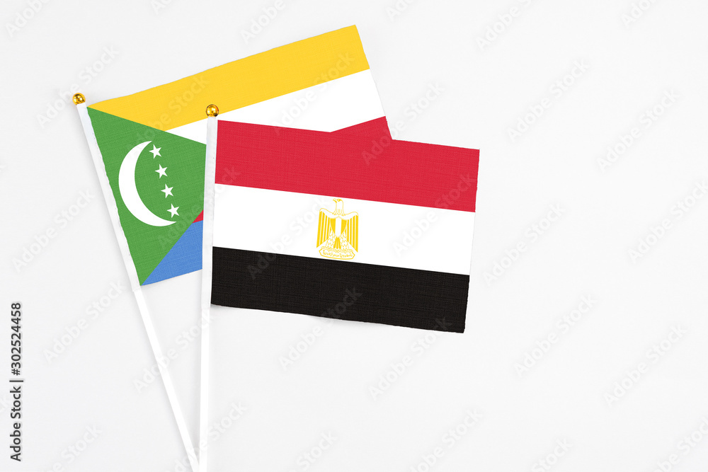 Egypt and Comoros stick flags on white background. High quality fabric, miniature national flag. Peaceful global concept.White floor for copy space. Egypt and Comoros stick flags on white background. High quality fabric, miniature national flag. Peaceful global concept.White floor for copy space.