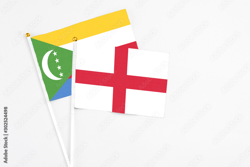 England and Comoros stick flags on white background. High quality fabric, miniature national flag. Peaceful global concept.White floor for copy space.