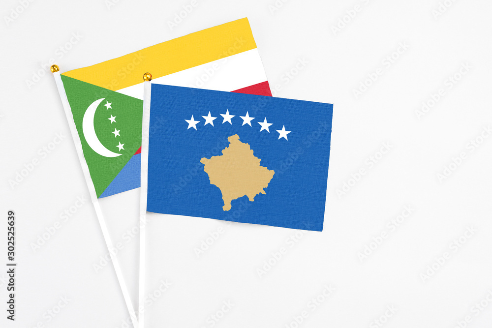 Kosovo and Comoros stick flags on white background. High quality fabric, miniature national flag. Peaceful global concept.White floor for copy space. Kosovo and Comoros stick flags on white background. High quality fabric, miniature national flag. Peaceful global concept.White floor for copy space.