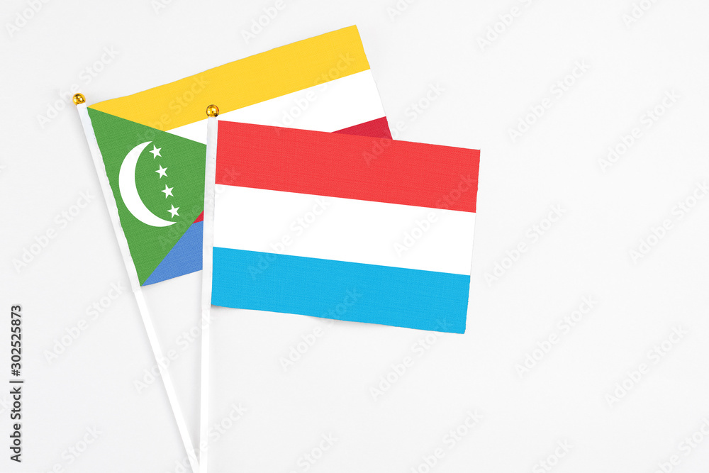 Luxembourg and Comoros stick flags on white background. High quality fabric, miniature national flag. Peaceful global concept.White floor for copy space. Luxembourg and Comoros stick flags on white background. High quality fabric, miniature national flag. Peaceful global concept.White floor for copy space.