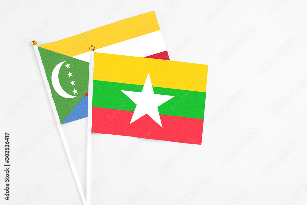 Myanmar and Comoros stick flags on white background. High quality fabric, miniature national flag. Peaceful global concept.White floor for copy space.