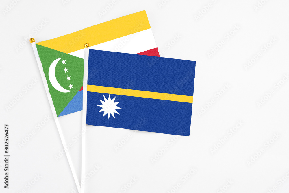 Nauru and Comoros stick flags on white background. High quality fabric, miniature national flag. Peaceful global concept.White floor for copy space.