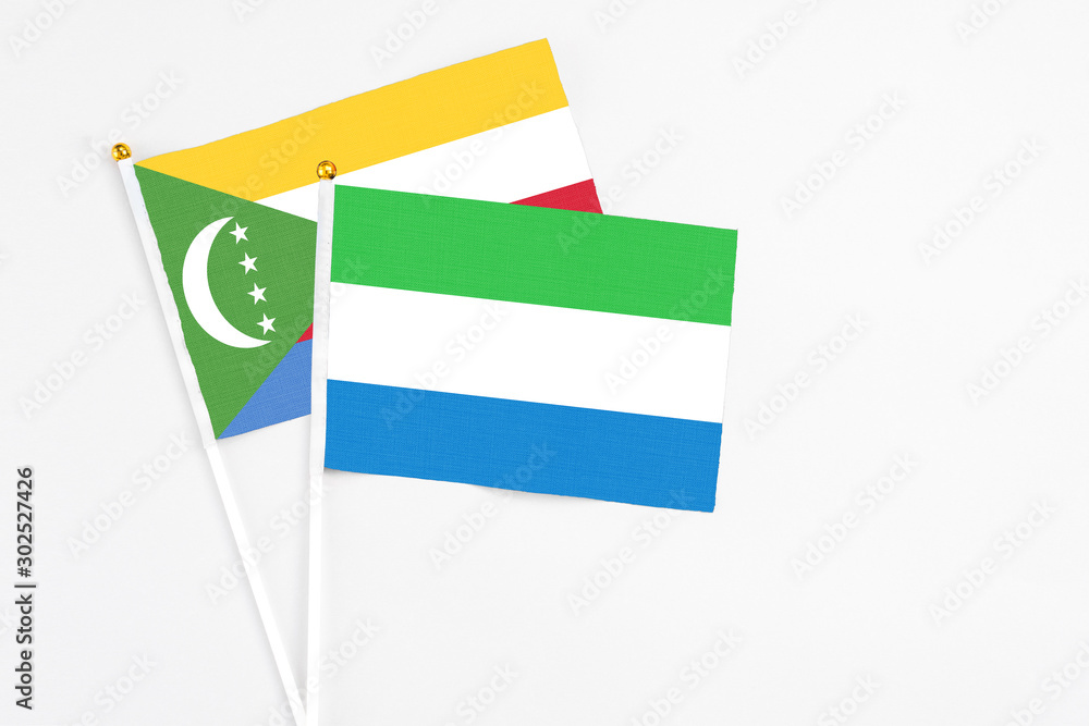 Sierra Leone and Comoros stick flags on white background. High quality fabric, miniature national flag. Peaceful global concept.White floor for copy space. Sierra Leone and Comoros stick flags on white background. High quality fabric, miniature national flag. Peaceful global concept.White floor for copy space.