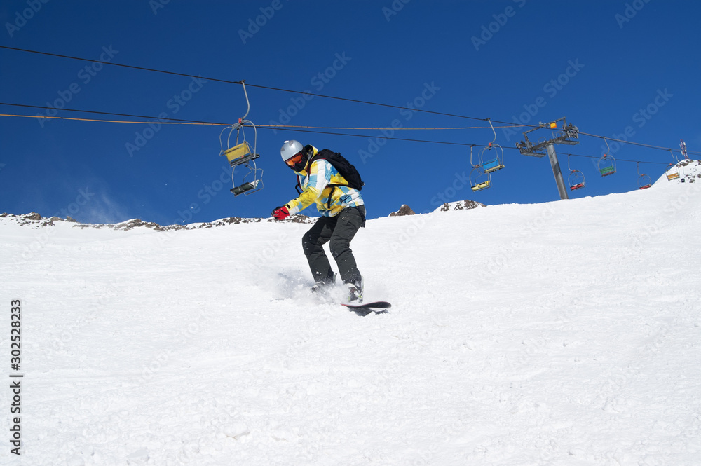 Snowboarder descends on snowy ski slope at winter mountains Snowboarder descends on snowy ski slope at winter mountains