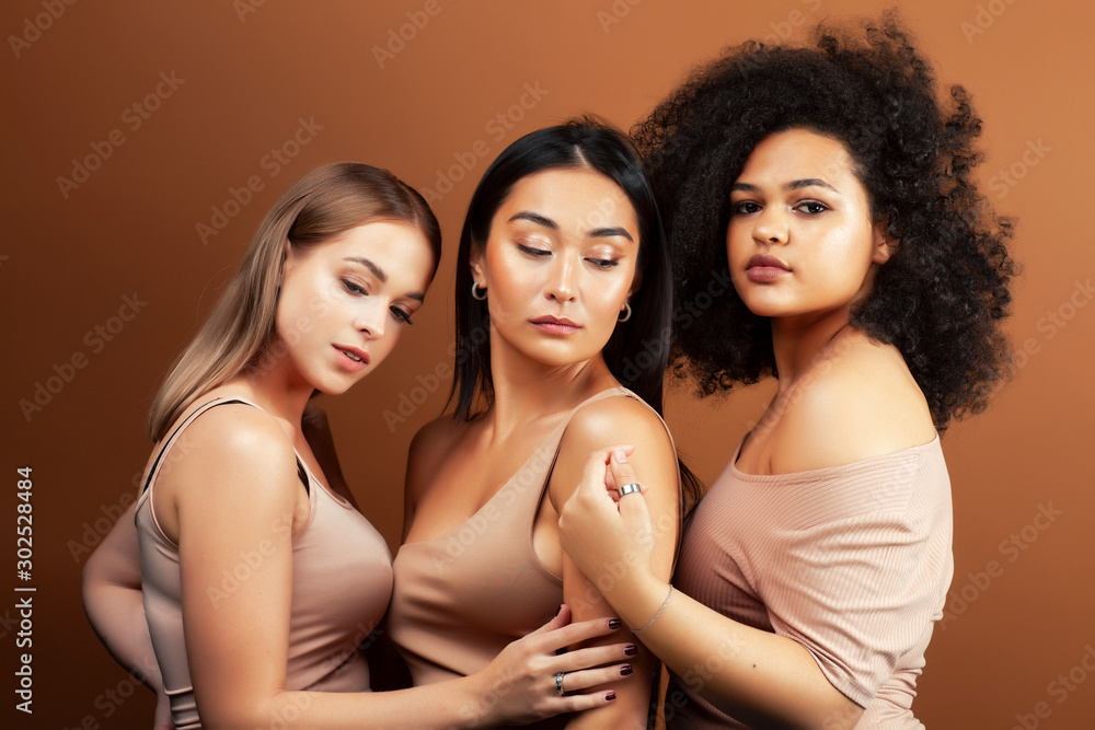 young pretty asian, caucasian, afro woman posing cheerful together on brown background, lifestyle diverse nationality people concept young pretty asian, caucasian, afro woman posing cheerful together on brown background, lifestyle diverse nationality people concept