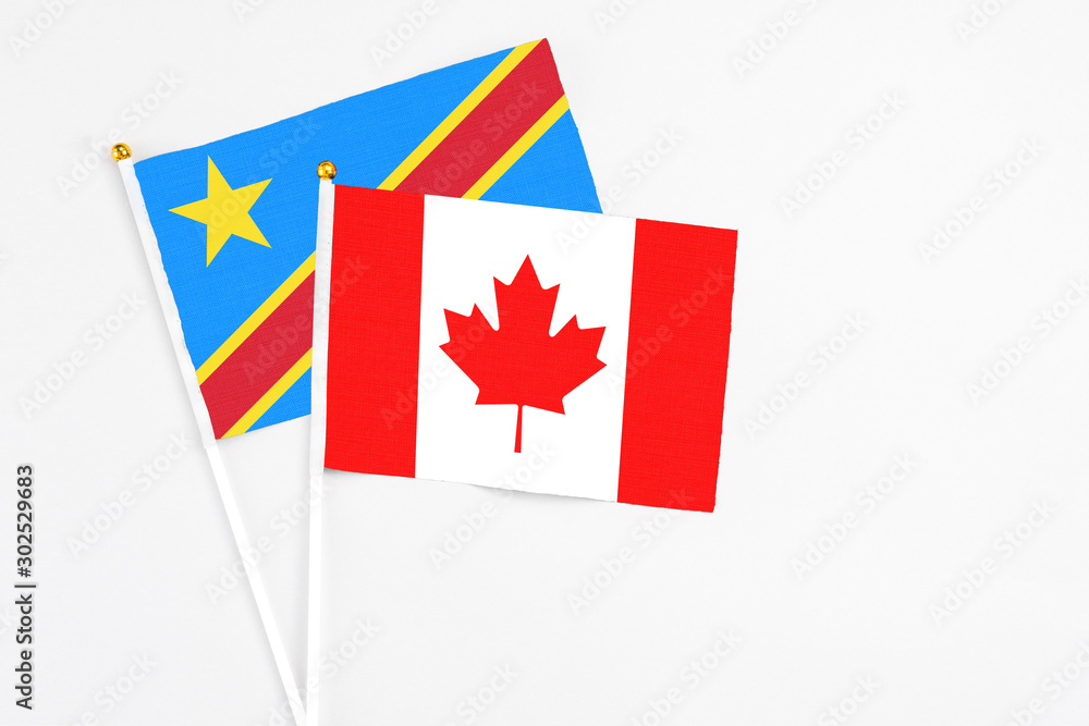Obraz premium Canada and Congo stick flags on white background. High quality fabric, miniature national flag. Peaceful global concept.White floor for copy space.