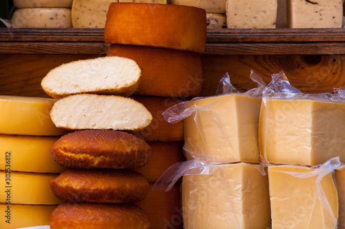 Variety of fresh packed and unpacked cheeses on a wooden shelf.