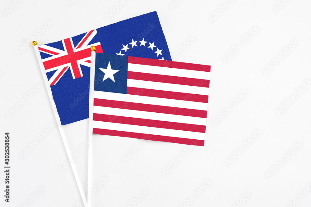 Liberia and Cook Islands stick flags on white background. High quality fabric, miniature national flag. Peaceful global concept.White floor for copy space. Liberia and Cook Islands stick flags on white background. High quality fabric, miniature national flag. Peaceful global concept.White floor for copy space.