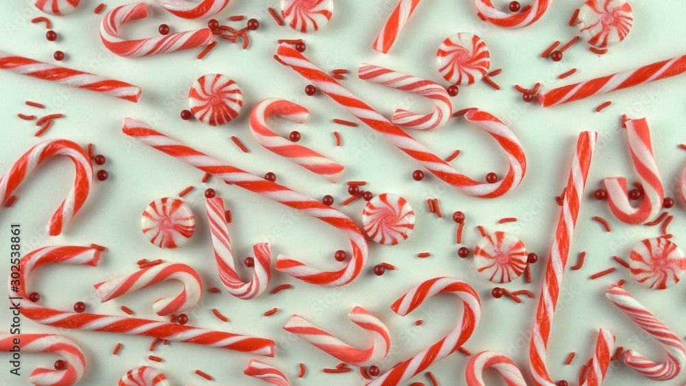 Christmas Eve holiday mood close up background. Winter Merry days  traditional ornament of candy canes and various gold sprinkles, peppermint and cinnamon lollipops. Top view.