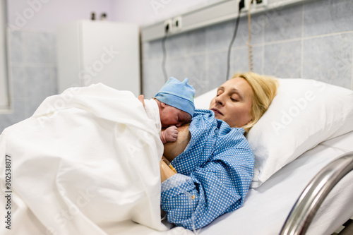 Mother and newborn baby laying and resting in hospital bed. After birth concept.