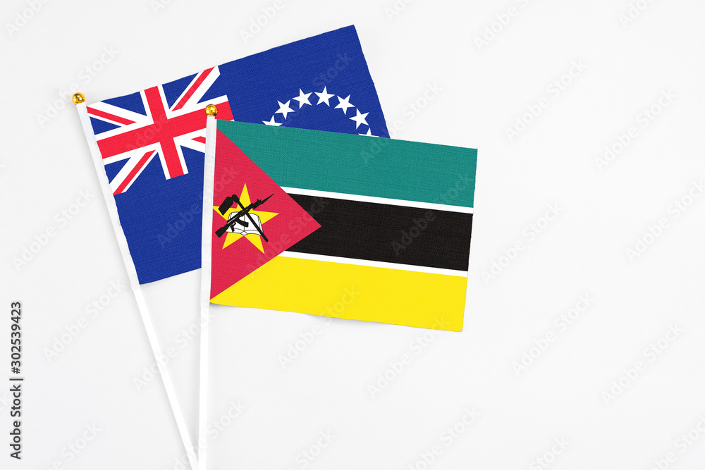 Mozambique and Cook Islands stick flags on white background. High quality fabric, miniature national flag. Peaceful global concept.White floor for copy space. Mozambique and Cook Islands stick flags on white background. High quality fabric, miniature national flag. Peaceful global concept.White floor for copy space.