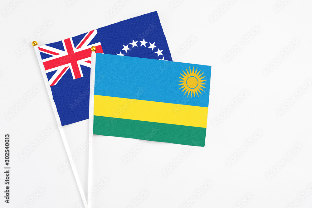 Rwanda and Cook Islands stick flags on white background. High quality fabric, miniature national flag. Peaceful global concept.White floor for copy space.